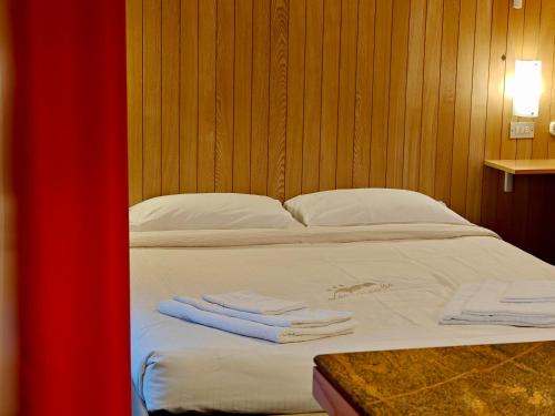 a bed with white sheets and two towels on it at Residence Les Coupoles in Champoluc