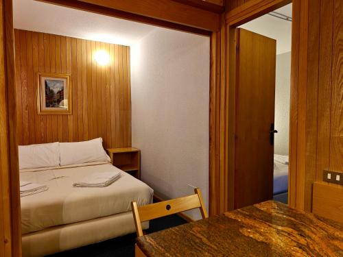 a small bedroom with a bed and a table at Residence Les Coupoles in Champoluc