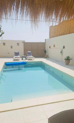 a large swimming pool with two chairs in it at Villa Dar Rayan & Naelle in Midoun