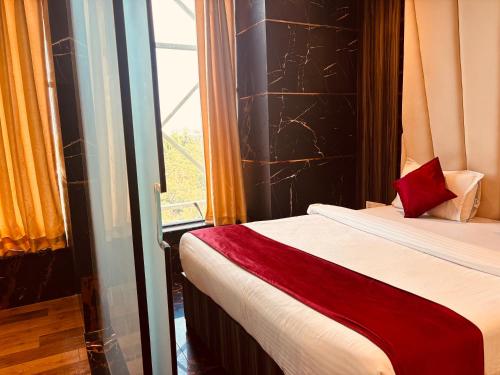 a bedroom with a bed with a red pillow and a window at Hotel Chariot Inn in Deoghar