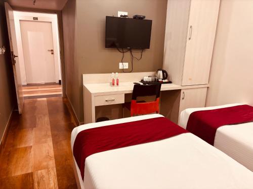 a hotel room with two beds and a desk and a tv at Hotel Chariot Inn in Deoghar