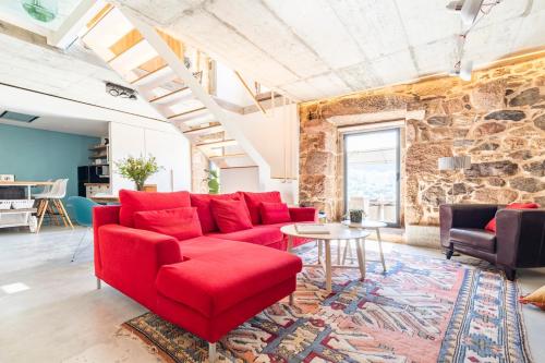 a living room with a red couch and a table at A casa dos Parladoiros in Mos