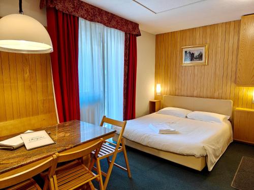 a hotel room with a bed and a desk and a table at Residence Les Coupoles in Champoluc