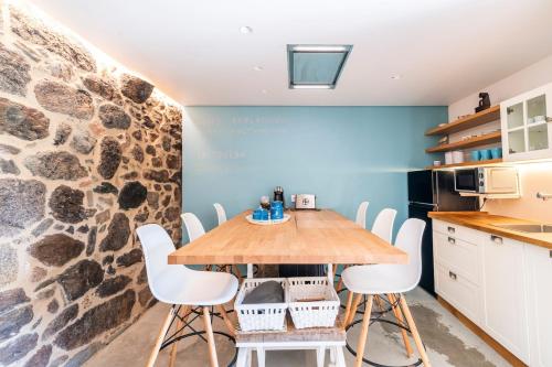 a kitchen with a wooden table and white chairs at A casa dos Parladoiros in Mos