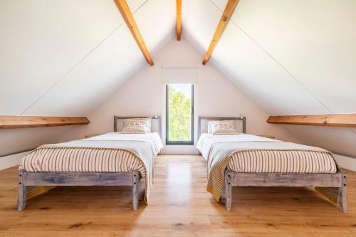two beds in a attic room with a window at A casa dos Parladoiros in Mos