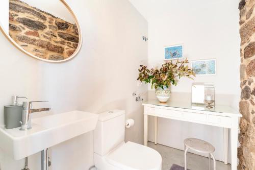 a bathroom with a sink and a toilet and a mirror at A casa dos Parladoiros in Mos