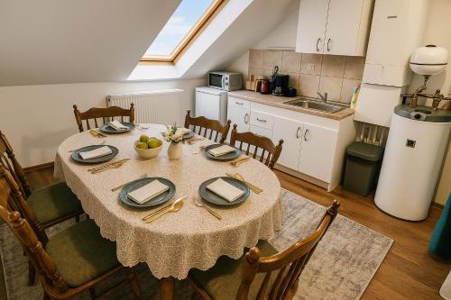 a dining room with a table and a kitchen at Joós Apartman in Sárvár