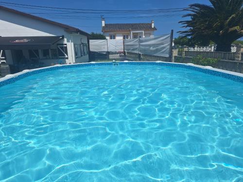 una gran piscina de agua azul frente a una casa en Villa Las Catedrales - Frente a la playa - Amplio jardín - Piscina, en Barreiros