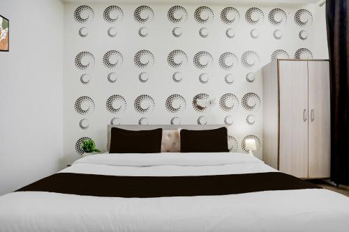 a bedroom with a white bed and a wall with plates at Hotel O Samridhi Inn in Varanasi
