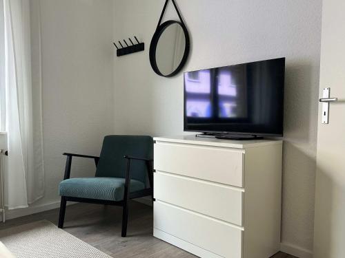 a bedroom with a tv and a chair and a mirror at 6P Zentrale Suite mit Balkon & Parkplatz in Witten