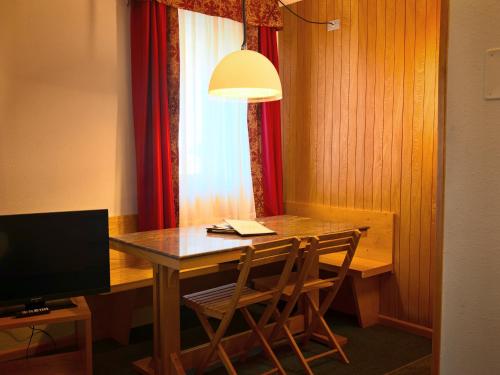 a dining room table with two chairs and a television at Residence Les Coupoles in Champoluc