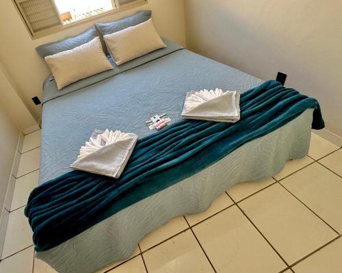 a bed with a blue blanket and white pillows at Apartamento Central in Passos