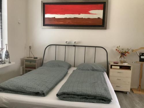 a bed with two pillows and a painting on the wall at 2 persoons appartement de luxe in Nijverdal