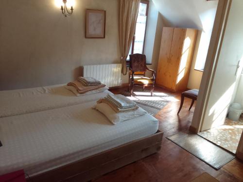 una camera con due letti e una sedia in una stanza di La bourguignonne a Villemanoche