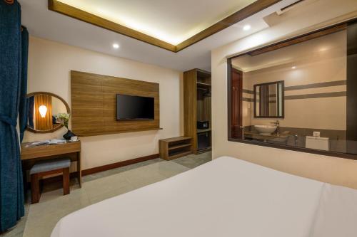 a hotel room with a bed and a television at NA Hotel Hoi An in Hoi An