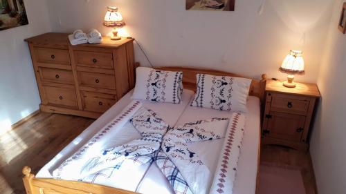 a bedroom with a bed and two dressers and two lamps at chalupa Slunovrat in Hroznětín