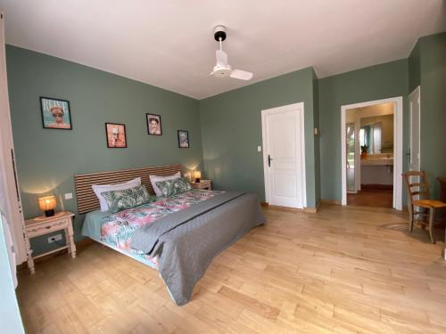 a bedroom with a bed with green walls and wooden floors at Petit Rousset Gite Noyer in Eymet