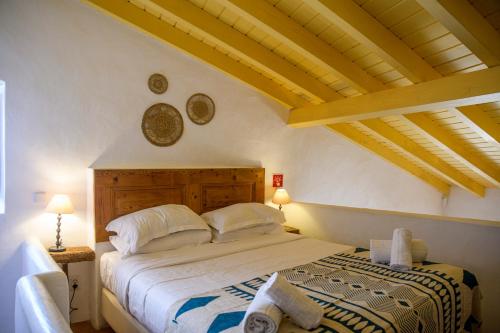 a bedroom with a bed in a room with wooden ceilings at Aldeia da Pedralva by WOT Signature in Vila do Bispo