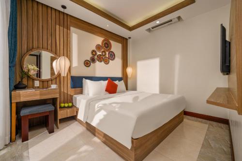 a bedroom with a bed and a desk and a mirror at NA Hotel Hoi An in Hoi An