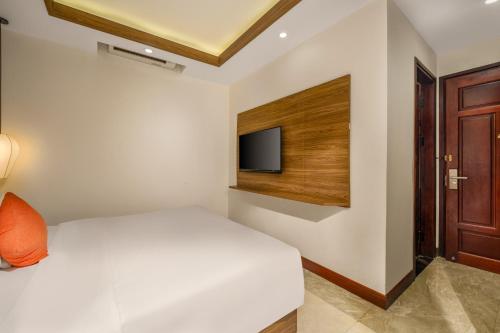 a bedroom with a bed and a tv on the wall at NA Hotel Hoi An in Hoi An