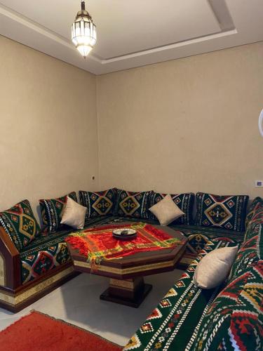 a living room with a couch with a table on it at taghoba surf house in Tamraght Ouzdar
