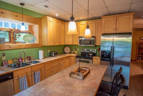 a kitchen with wooden cabinets and a kitchen island with a sink at Rock n Rhapsody - Blue Ridge Log Cabin - Minutes to West Jefferson - Fireplace - Foosball in West Jefferson