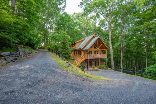a log cabin in the woods with a driveway at Rock n Rhapsody - Blue Ridge Log Cabin - Minutes to West Jefferson - Fireplace - Foosball in West Jefferson