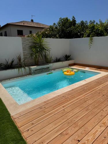 Villa Nyss في لونيه: حمام سباحة مع سطح خشبي وقرص طائر بداخله
