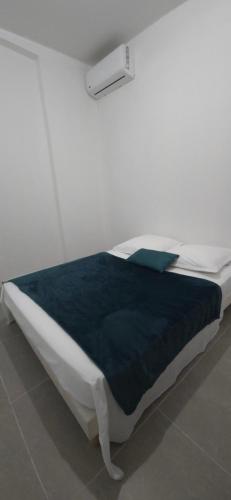 a white bed with a blue blanket on top of it at La Fleur Dore in Le Vauclin