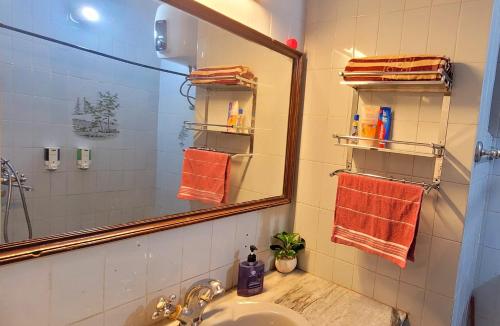 a bathroom with a sink and a mirror and towels at RB Cottage at mall road mussoorie in Mussoorie