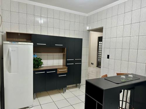 a kitchen with black cabinets and a white tiled wall at Apartamento Central in Passos