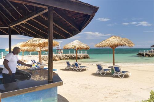 a man sitting at a table on the beach at Grand Muthu Runaway Bay Club Caribbean in Runaway Bay