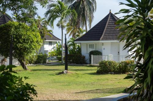 a white house with palm trees in a yard at Grand Muthu Runaway Bay Club Caribbean in Runaway Bay
