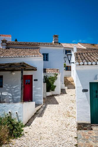 a group of white houses with red doors in a street at Aldeia da Pedralva by WOT Signature in Vila do Bispo