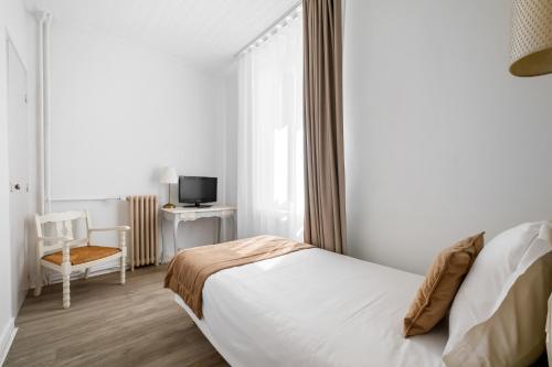 a bedroom with a bed and a window and a chair at Hotel Saint Paul in Noirmoutier-en-l'lle