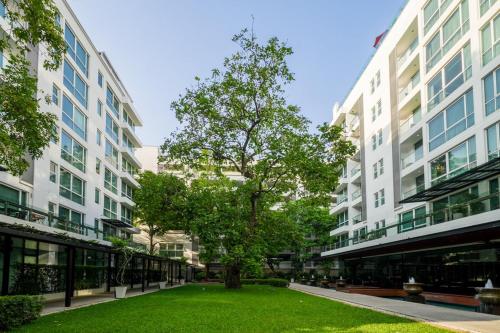 a green lawn in front of two tall buildings at Shama Petchburi 47 Bangkok in Bangkok