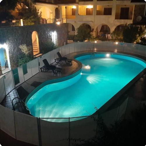 a swimming pool at night with two chairs around it at Casa Bella Vista in Villasimius