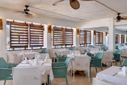 a restaurant with white tables and chairs and windows at Grand Muthu Runaway Bay Club Caribbean in Runaway Bay