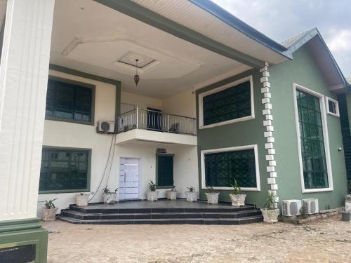 a green and white house with potted plants at Platinum Palace Home in Benin City