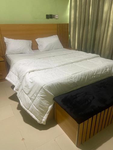 a large bed with white sheets in a bedroom at Platinum Palace Home in Benin City