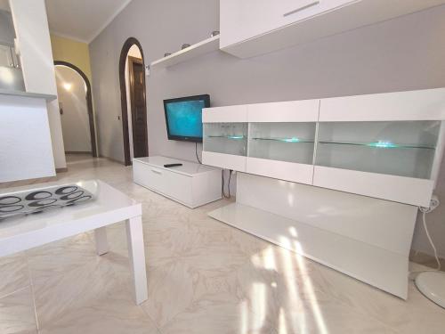 cocina blanca con fogones y TV en Rincón en el centro de Palamós, en Palamós