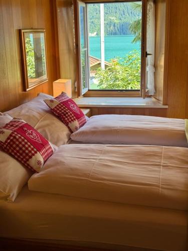 two beds sitting in a room with a window at Historic Lakeview Swiss Chalet near Interlaken in Niederried