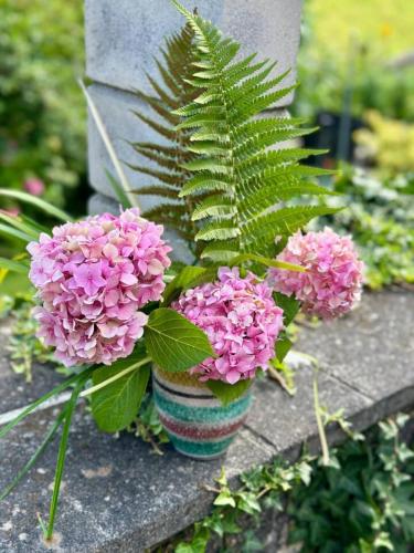 a vase filled with pink flowers and a plant at Historic Lakeview Swiss Chalet near Interlaken in Niederried