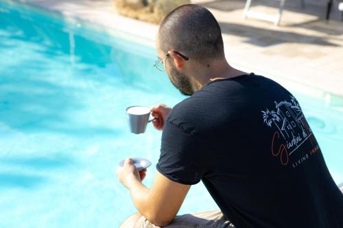 a man sitting by a pool holding a cup of coffee at Bed & Breakfast Giardini Di Marzo in Lecce