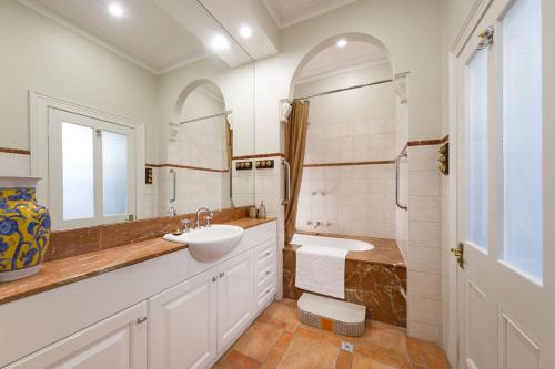 a white bathroom with a sink and a mirror at Porters Cottage Grande (two units) in Albury