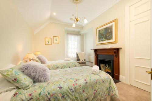 a bedroom with two beds and a fireplace at Porters Cottage Grande (two units) in Albury