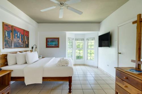 a bedroom with a white bed and a television at Grand Muthu Runaway Bay Club Caribbean in Runaway Bay