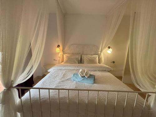 ein Bett mit weißen Vorhängen und einem blauen Handtuch darauf in der Unterkunft Delicate child friendly ground floor apartment in Mijas Costa