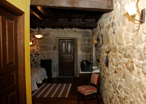 a room with a stone wall and two chairs and a door at Casa Casarellos in Casarellos