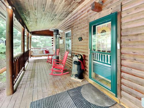 a wooden porch with red chairs and a blue door at Wander Through the Woods in McHenry